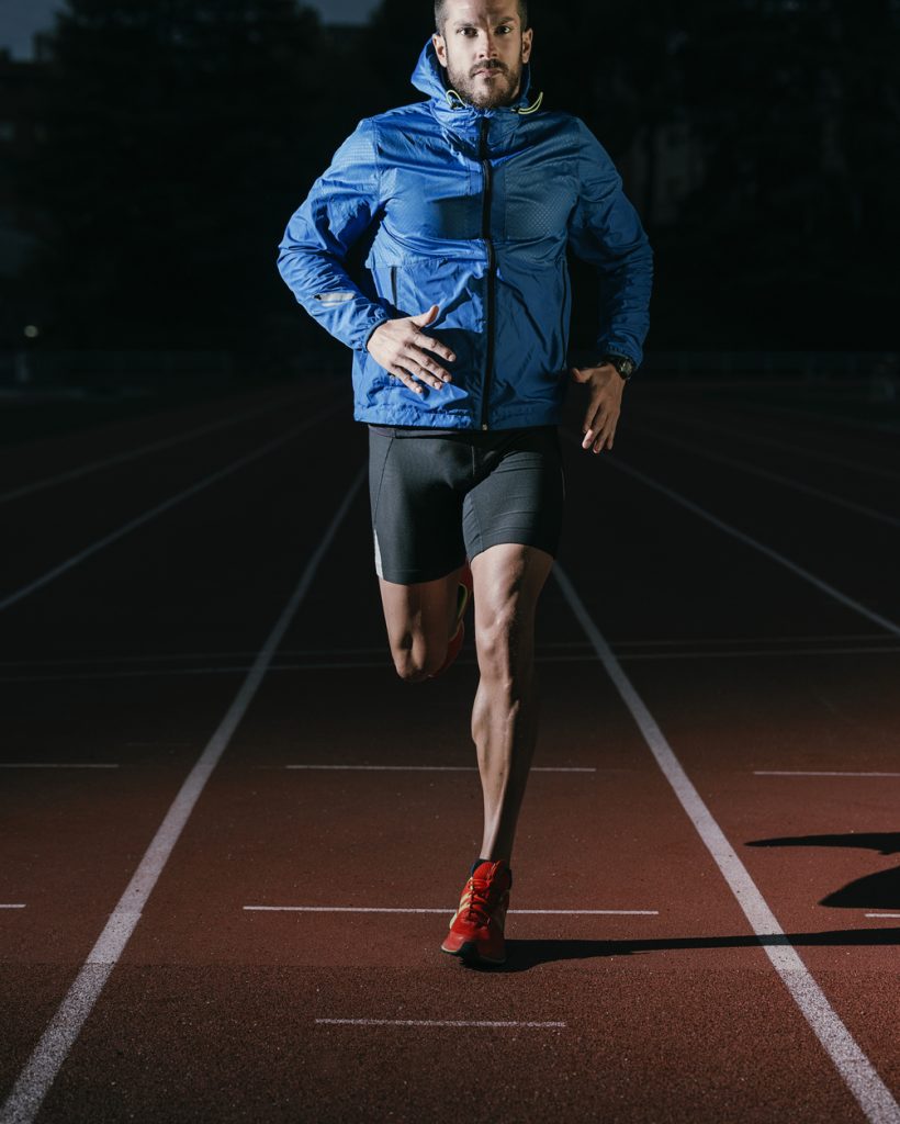 Attractive man Track Athlete Running On Track looking camera