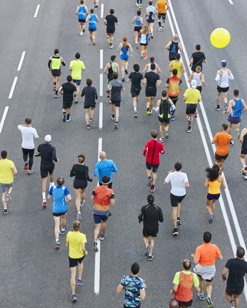 Runners on the street. Athletes in motion. Urban competition. Vertical